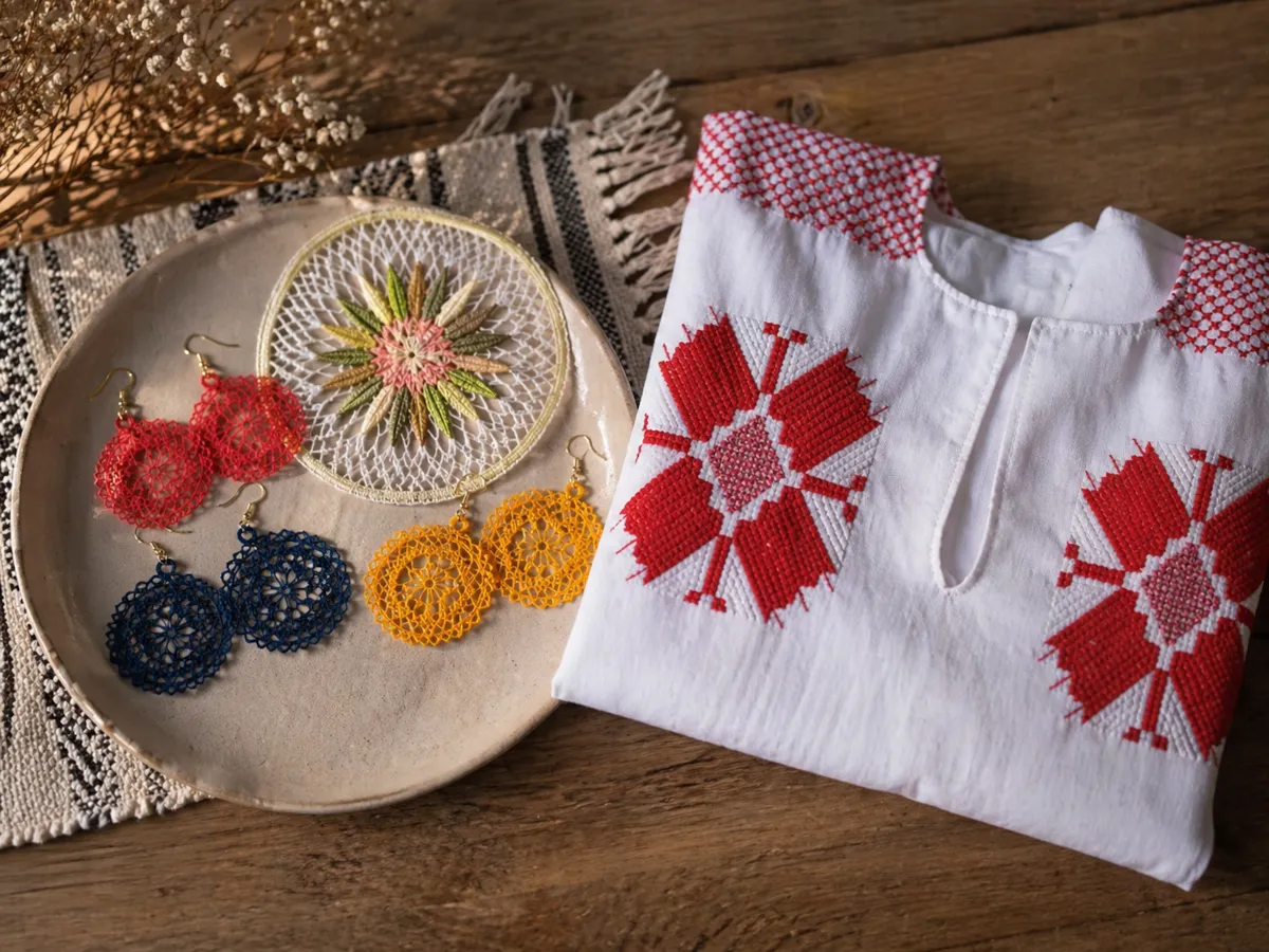 Ñandutí-Schmuck und ein weißes Ao Po’i-Kleidungsstück mit roter Stickerei auf einem Holztisch
